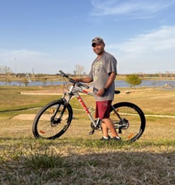 Photo of Veteran Aquinas Kenrog holding his bicycle