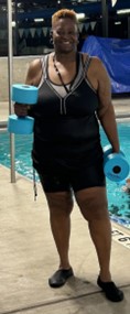 Photo of Vickie standing with weights by a pool.