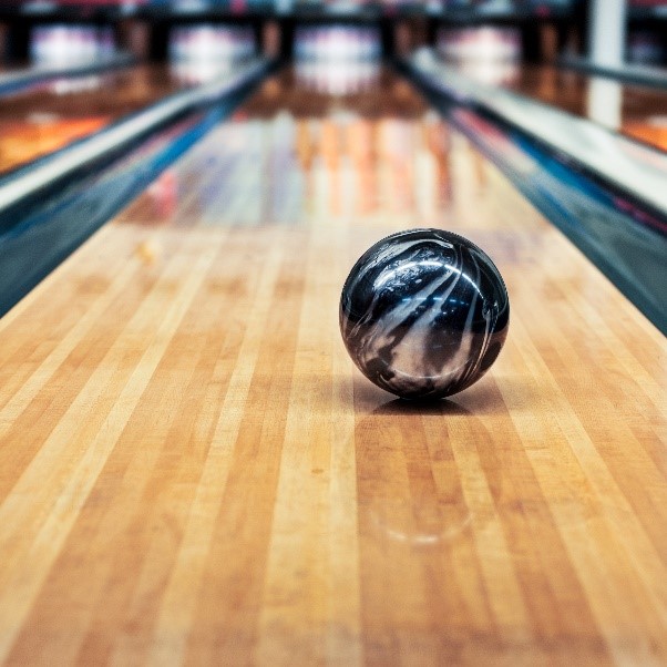 Photo of a black and silver bowling ball rolling down the lane