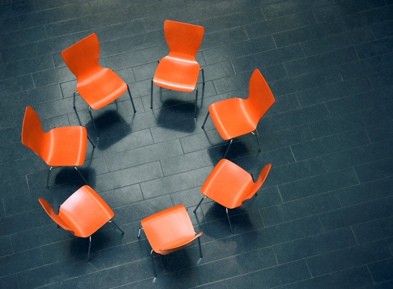 Photo of empty orange chairs forming a circle