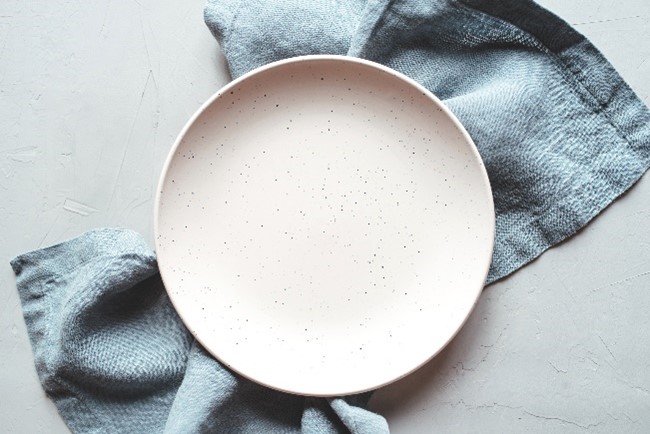 Photo of empty ceramic plate on gray napkin
