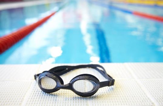 Photo of Swimming goggles on the side of a lap pool