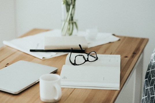 Photo of workspace table with tablet eyeglasses schedule calendar and cup
