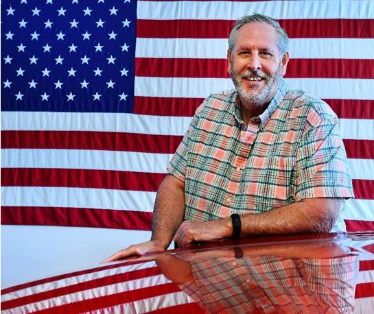 Photo of the Veteran pictured in front of the American flag.