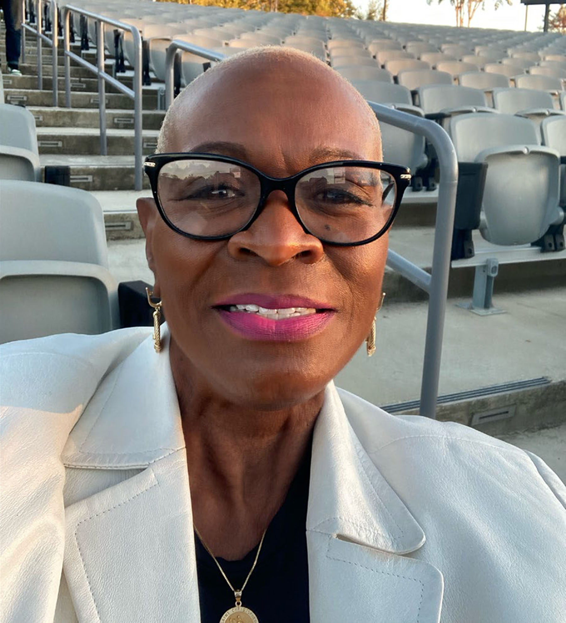Photo of Carolyn Polk smiling, sitting in stadium seating.