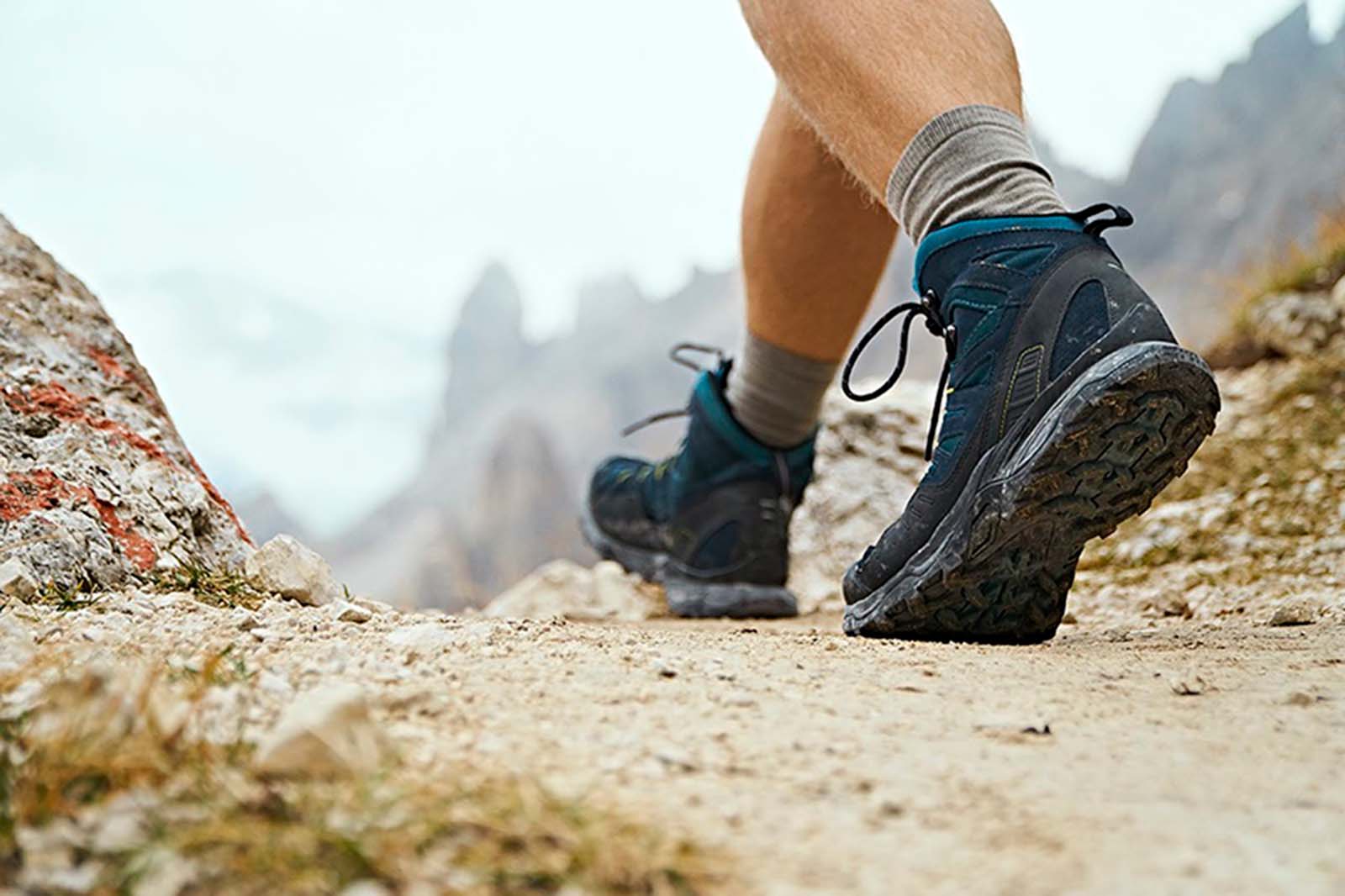 Photo of a person's hiking boots from behind while walking along an elevated trail.