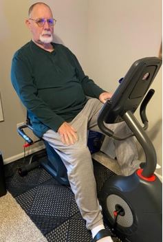 This is a photo of the Veteran on a stationary, recumbent exercise bike.