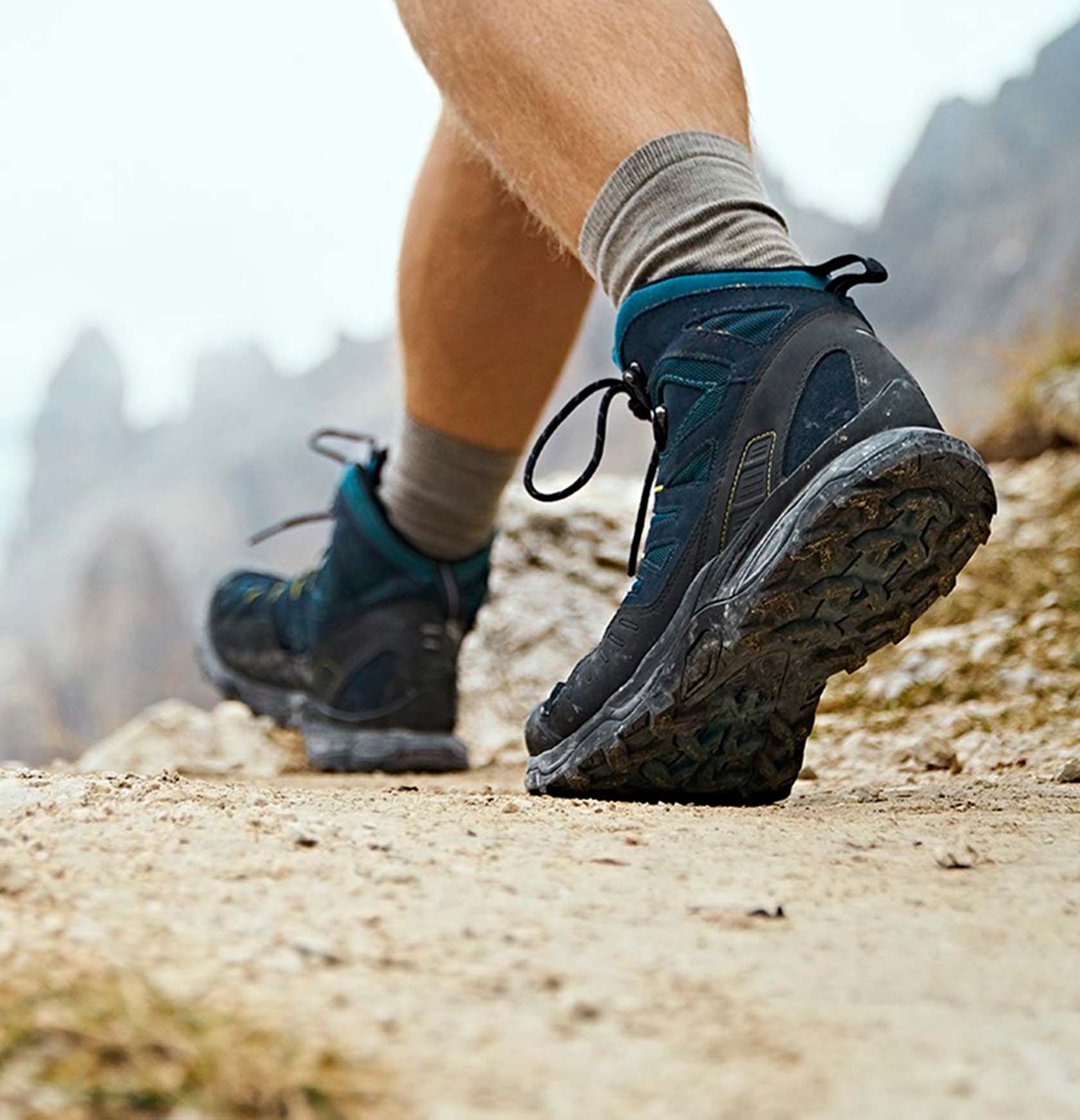 Photo of a person's hiking boots from behind while walking along an elevated trail.