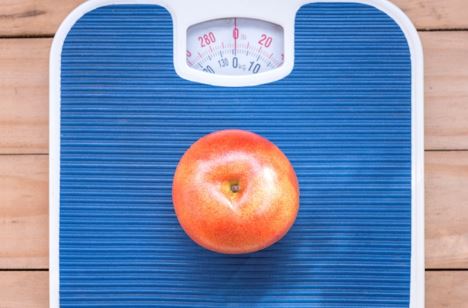 Photo of red apple on blue weighing scale