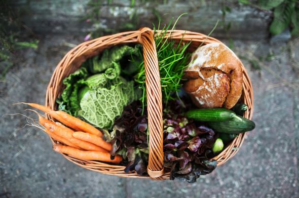 Photo of basket with veggies and bread placed outdoors