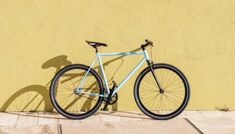 Photo of a bicycle leaning on a yellow wall.